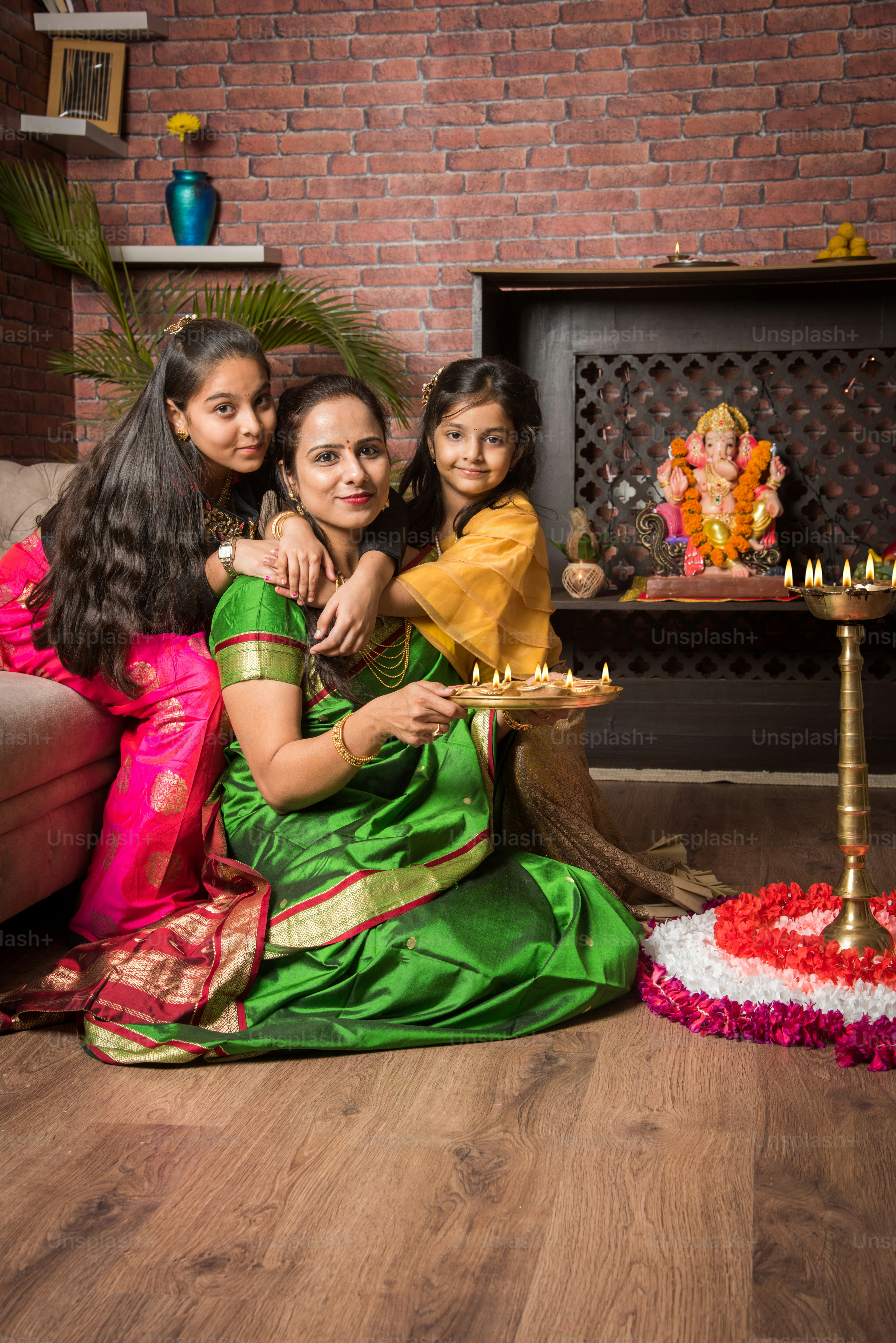 Mother and daughter making flower rangoli and girl lighting diya or ...