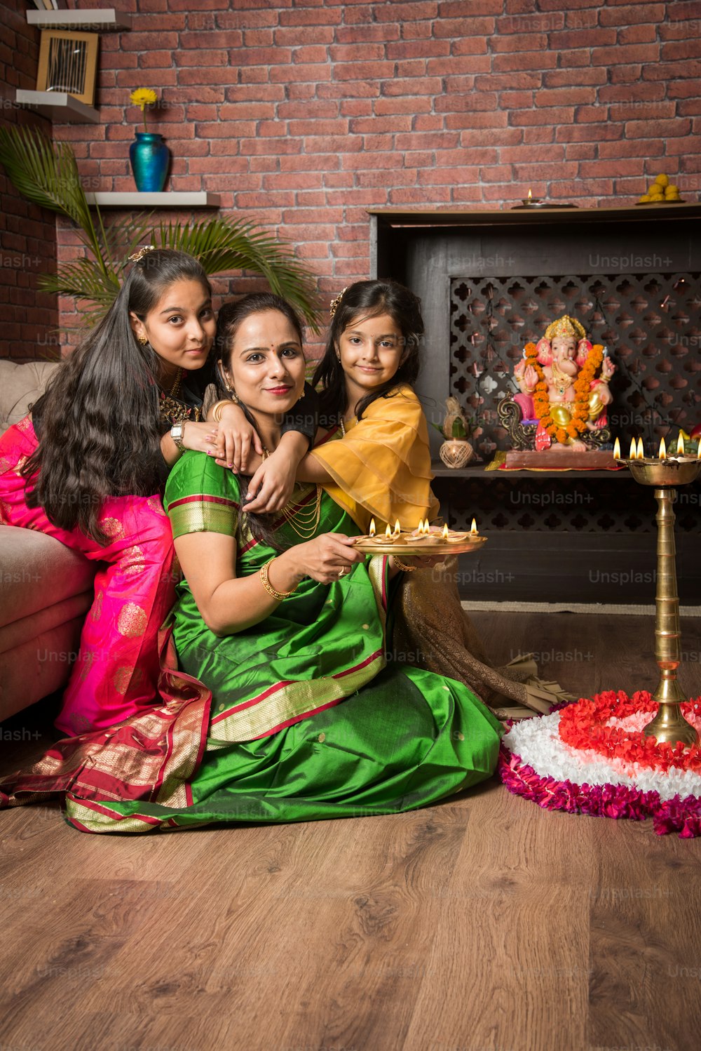 Mother and daughter making flower rangoli and girl lighting diya or samai