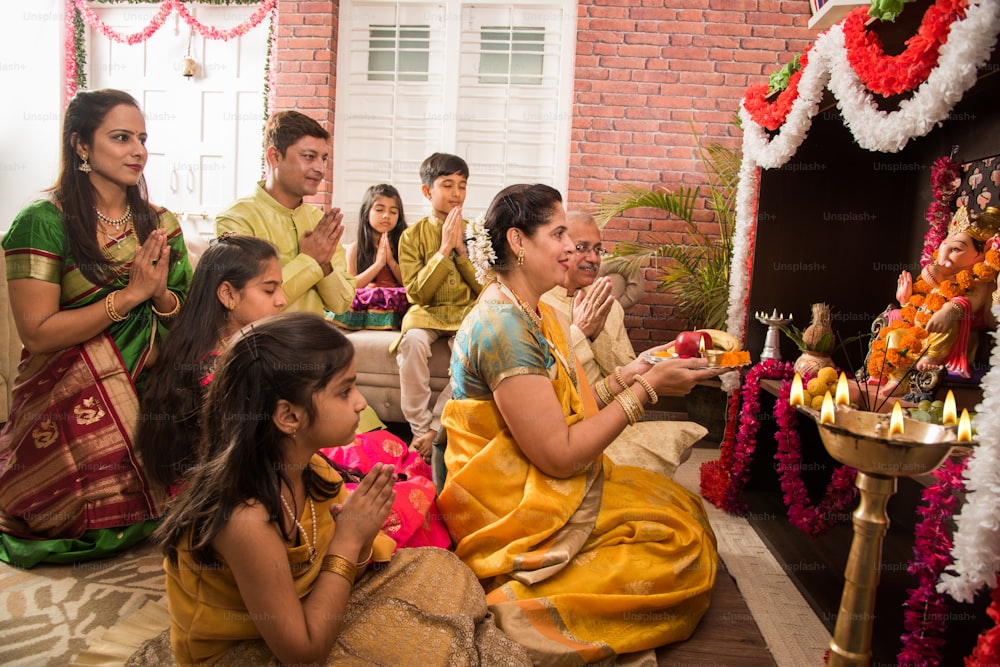 ガネーシャ・ウツァフでガネーシャ・プジャまたはガンパティ・プジャを行うインドの家族、または白い背景にガネーシャの偶像を持つ