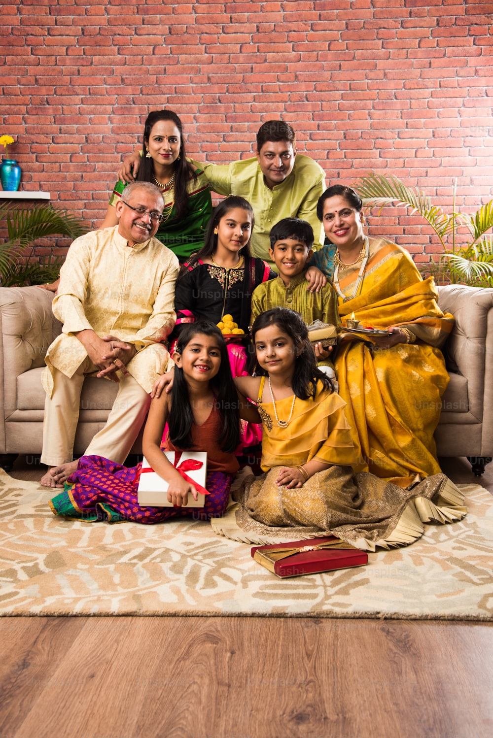 Retrato de una familia india feliz en ropa tradicional sentada en el sofá interior