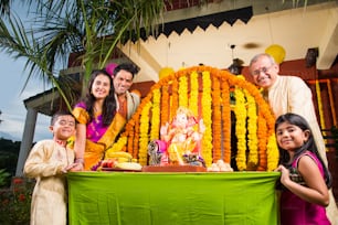 cheerful indian family welcoming lord Ganesha idol on ganesh festival or ganesh chaturthi on palkhi decorated with garland flowers