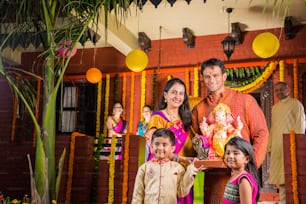 cheerful indian family welcoming lord Ganesha idol on ganesh festival or ganesh chaturthi on palkhi decorated with garland flowers