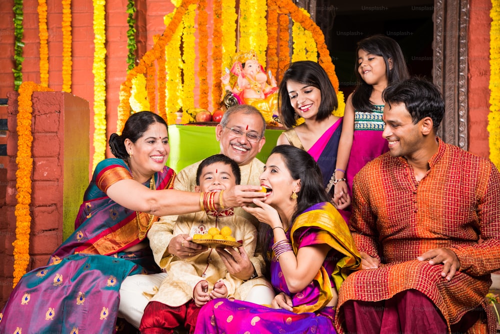 Gruppenfoto einer fröhlichen indischen Familie, die süße Begegnungen oder Laddu auf dem Ganesh-Festival, der glücklichen indischen Familie und der Ganpati-Festival-Feier isst