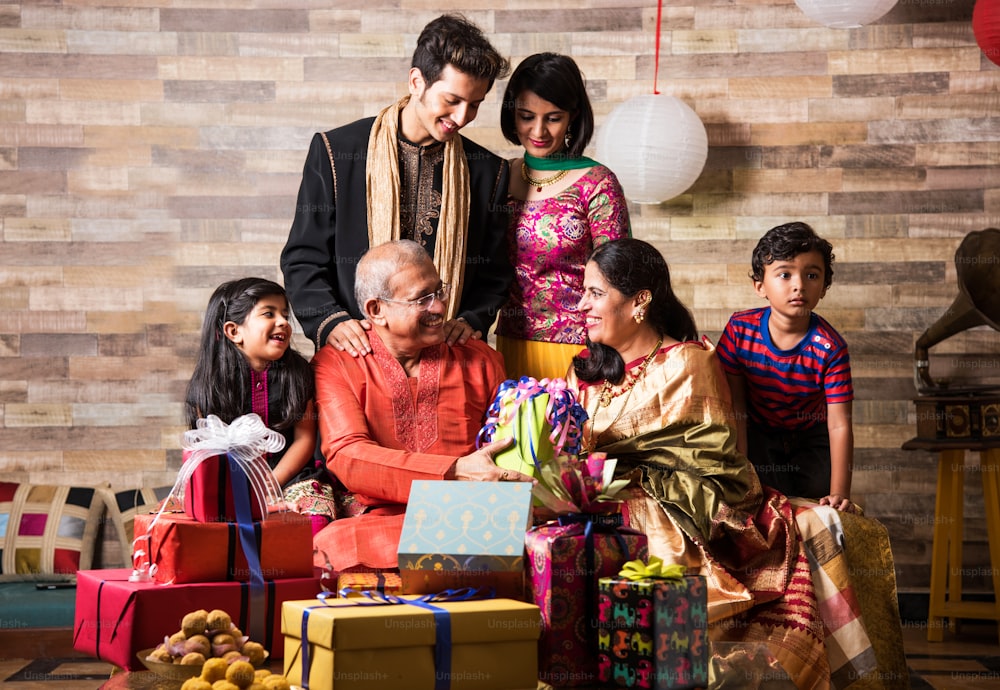 Família indiana celebrando festival de diwali ou aniversário trocando presentes, 3 gerações de família indiana e presentes e doces, conceito de felicidade