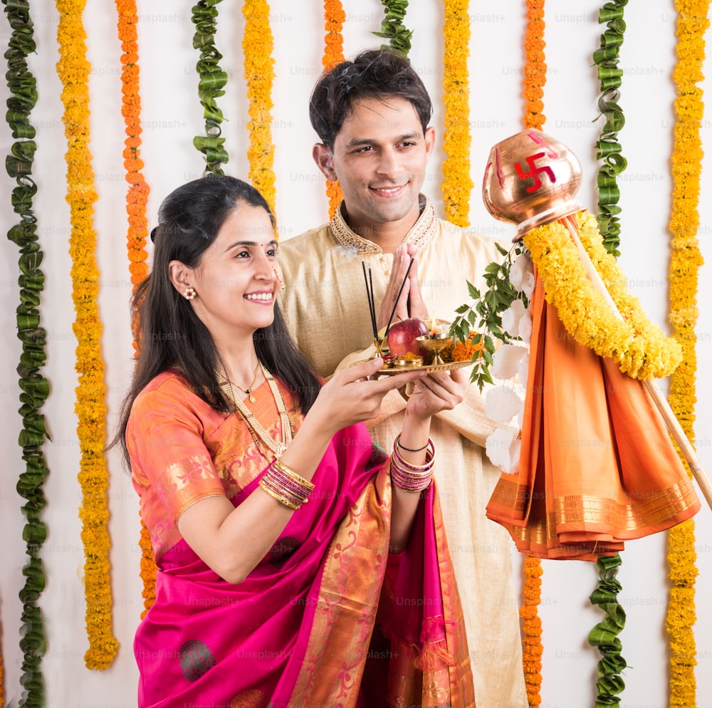 Kluges indisches Paar, das Gudhi Padwa Puja, asiatisches Paar und Puja Thali, indisches junges Paar, das Puja oder Pooja durchführt, hinduistisches Neujahrsfest Gudhi Padwa / Gudi Padwa, indisches Paar, das in traditioneller Kleidung betet