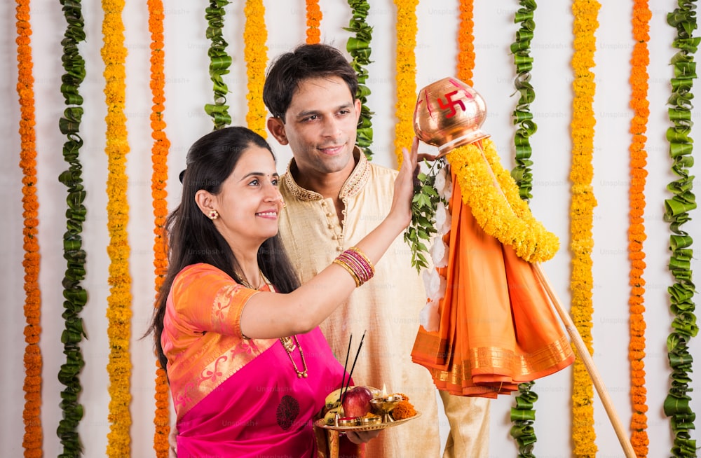 smart indian couple doing gudhi padwa puja, asian couple & puja thali, indian young couple performing puja or pooja, hindu new year gudhi padwa / gudi padwa, indian couple praying in traditional wear