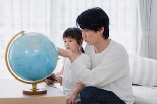 Family studying with dad using a globe