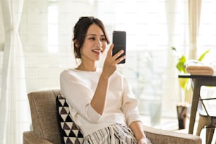 Mujer joven usando un teléfono inteligente en su habitación