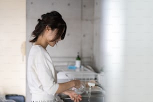 Giovane donna che lava i piatti a casa