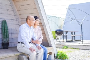Una pareja de ancianos sentada frente a su casa de vacaciones