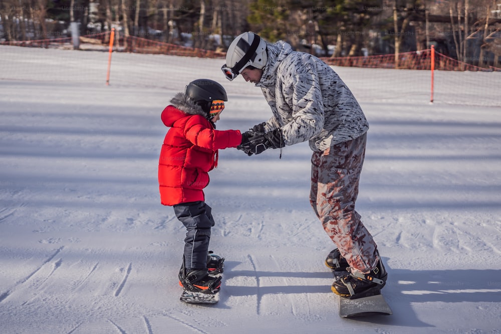 Kleiner süßer Junge beim Snowboarden. Aktivitäten für Kinder im Winter. Wintersport für Kinder. Lebensstil.