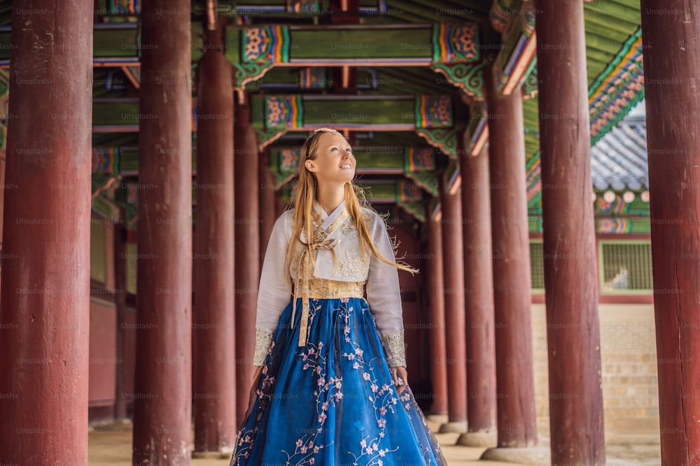 Junge kaukasische Touristin in Hanbok nationales koreanisches Kleid im koreanischen Palast. Reise-nach-Korea-Konzept. Nationale koreanische Kleidung. Unterhaltung für Touristen - Anprobieren nationaler koreanischer Kleidung.
