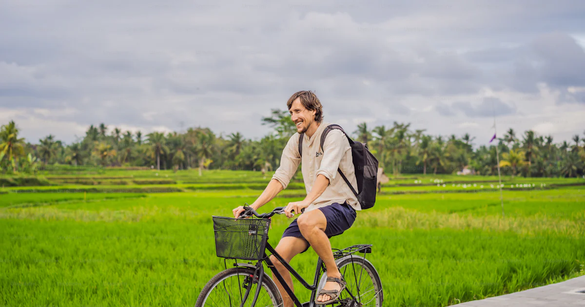 A young man rides a bicycle on a rice field in Ubud, Bali. Bali Travel ...