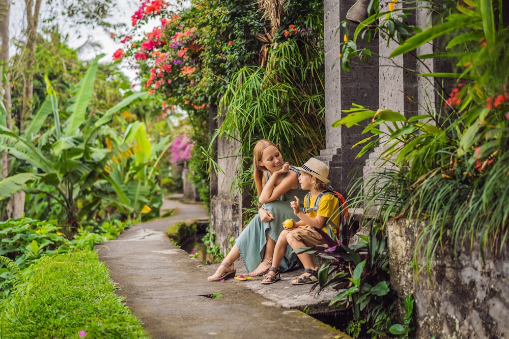 Mutter-Sohn-Touristen in Bali spazieren durch die engen, gemütlichen Gassen von Ubud. Bali ist ein beliebtes Touristenziel. Reisen Sie nach Bali. Konzept des Reisens mit Kindern.
