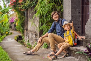 バリ島の父と息子の観光客は、ウブドの狭い居心地の良い通りを歩きます。バリ島は人気のある観光地です。バリへの旅行のコンセプト。子供との旅行のコンセプト。