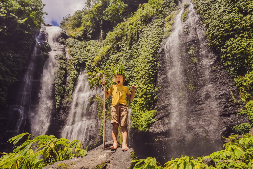 Cute boy depicts the king of the jungle against the backdrop of a waterfall. Childhood without gadgets concept. Traveling with children concept. Childhood outdoors concept.