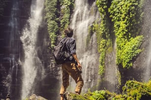 Man in turquoise dress at the Sekumpul waterfalls in jungles on Bali island, Indonesia. Bali Travel Concept.