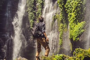 Uomo in abito turchese alle cascate di Sekumpul nella giungla sull'isola di Bali, in Indonesia. Concetto di viaggio a Bali.