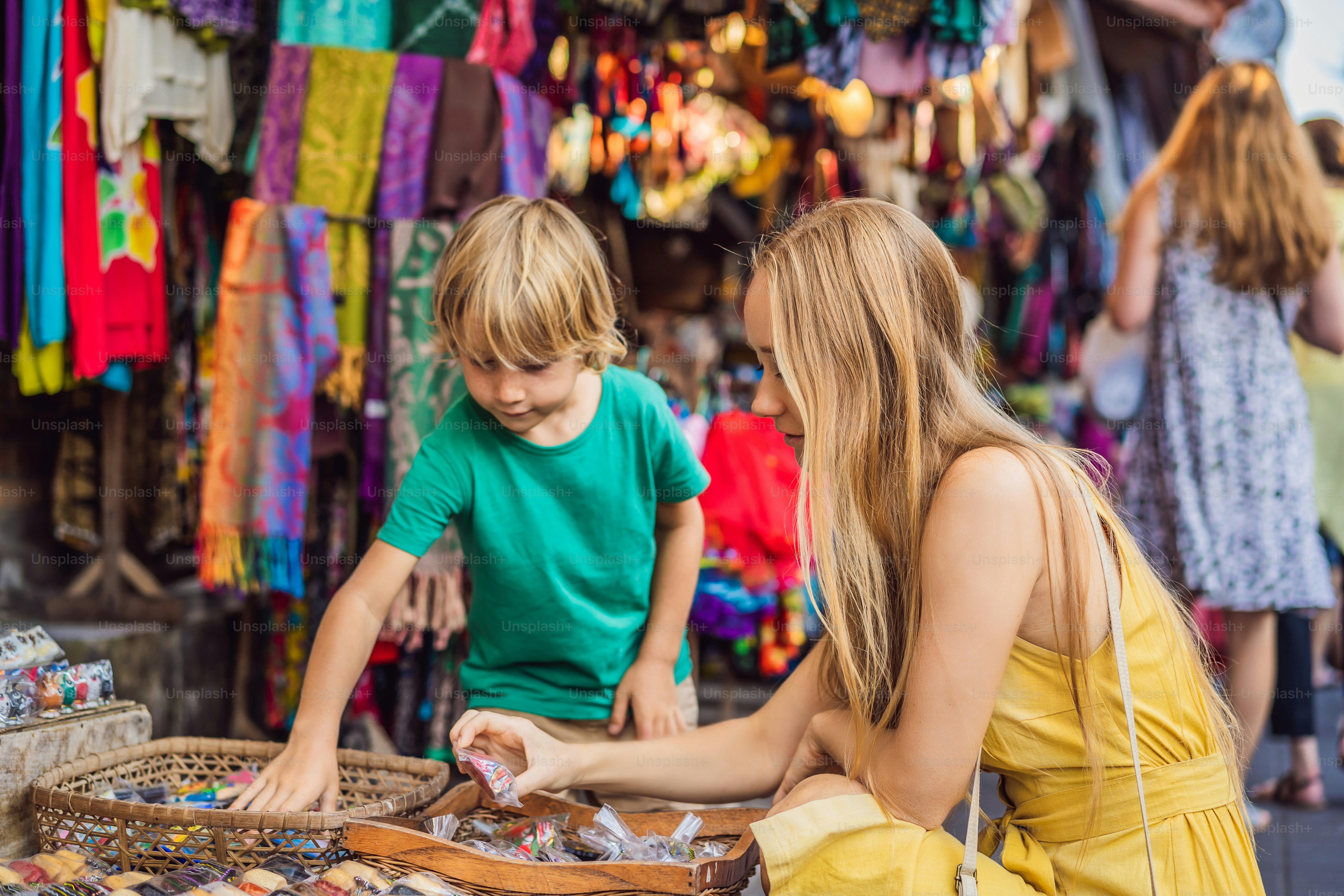 Mom and son travelers choose souvenirs in the market at Ubud in Bali, Indonesia.
