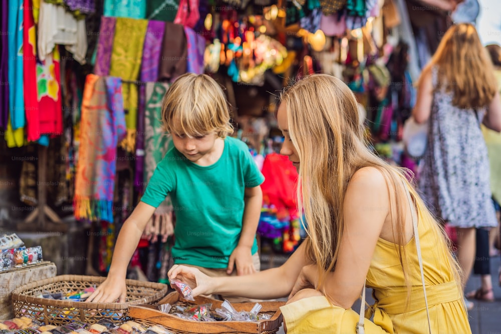Mom and son travelers choose souvenirs in the market at Ubud in Bali, Indonesia.