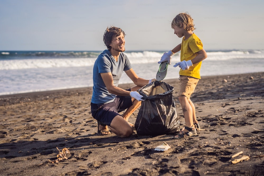Dad and son are cleaning up the beach. Natural education of children.