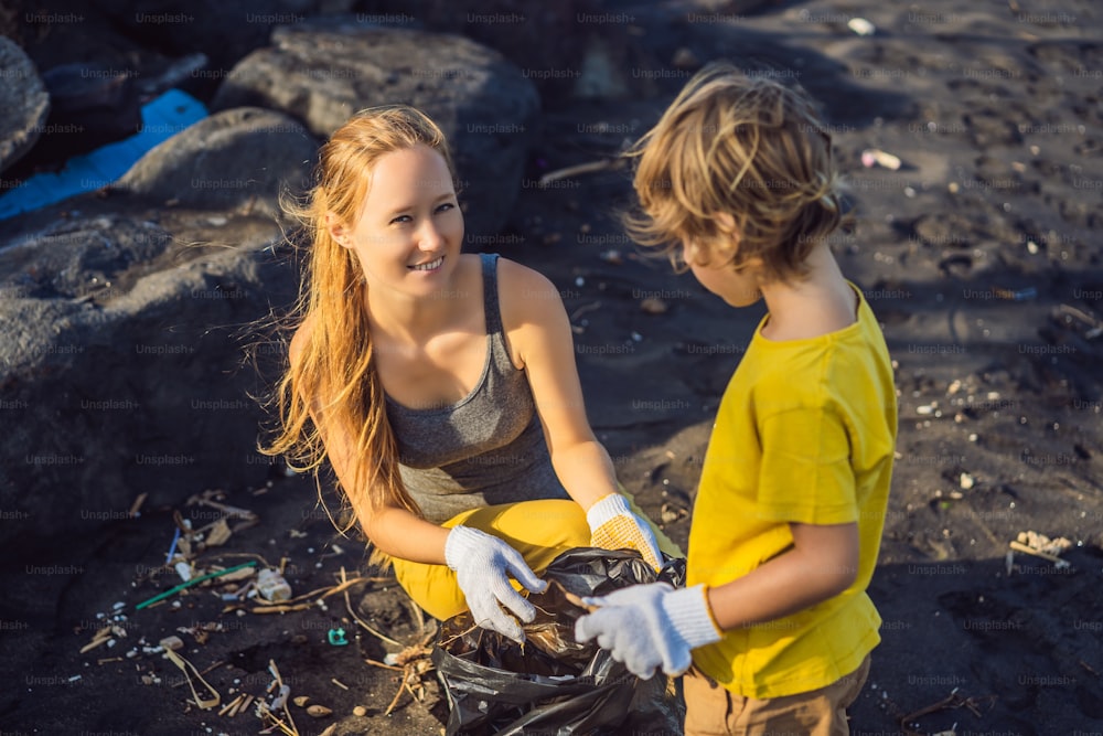 Madre e figlio stanno pulendo la spiaggia. Educazione naturale dei bambini.