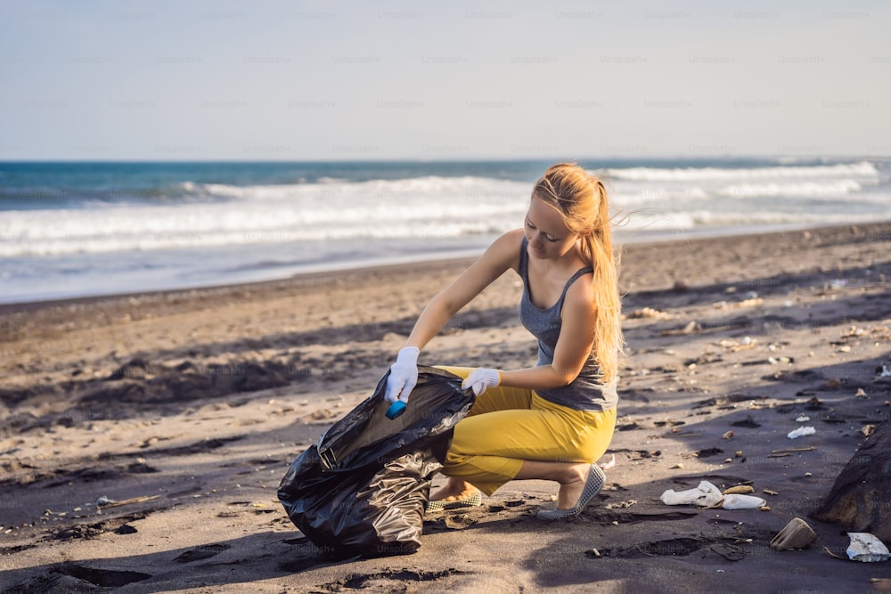 Young woman cleaning up the beach. Natural education of children.