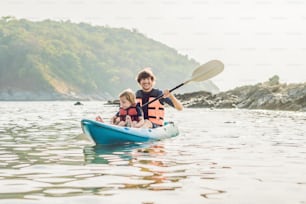 Padre e hijo navegando en kayak en el océano tropical. Concepto de viajes y actividades con niños.