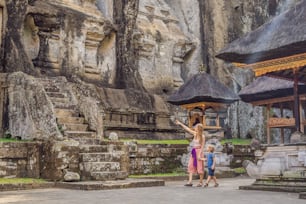 Mom and son on background of Gunung Kawi. Ancient carved in the stone temple with royal tombs. Bali, Indonesia. Traveling with children concept..