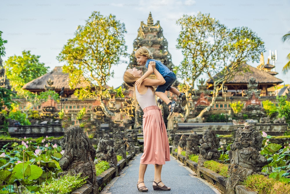 Mom and son travelers in the background of Pura Taman Kemuda Saraswati Temple in Ubud, Bali island, Indonesia. Traveling with children concept