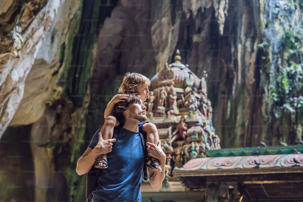 Vater und Sohn im Hintergrund der Batu-Höhlen in der Nähe von Kuala Lumpur, Malaysia. Konzept des Reisens mit Kindern.