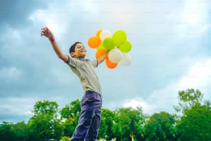 little indian school boy Jumping in sky with tri color balloons and celebrating Independence or Republic day of India