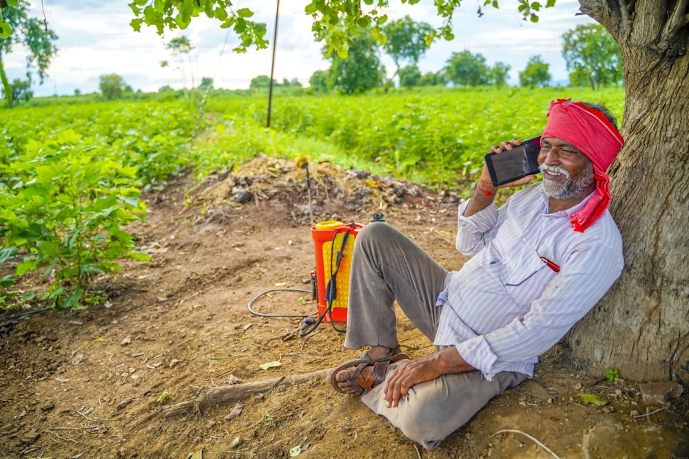 Agricultor indio hablando por teléfono móvil en el campo de la agricultura