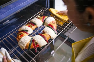 mexican woman baking a traditional rosca de reyes or epiphany cake on the oven in kitchen at home for Kings Day in Mexico Latin America