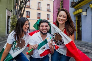 Grupo de mexicanos felices sosteniendo banderas en fiesta mexicana
