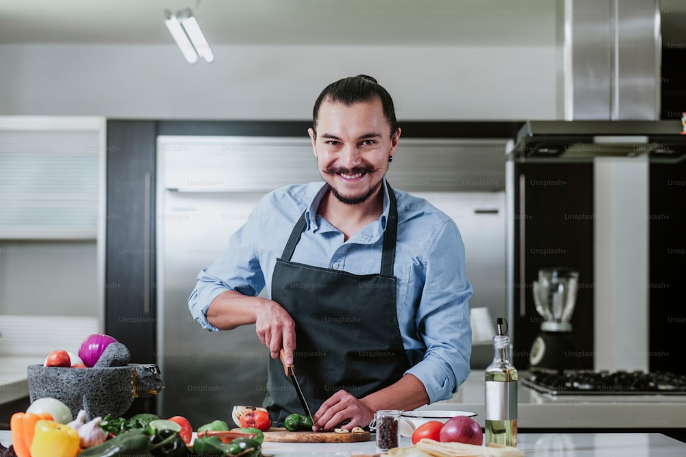 Uomo latino che cucina a casa preparando insalata o salsa messicana in cucina a casa a Città del Messico