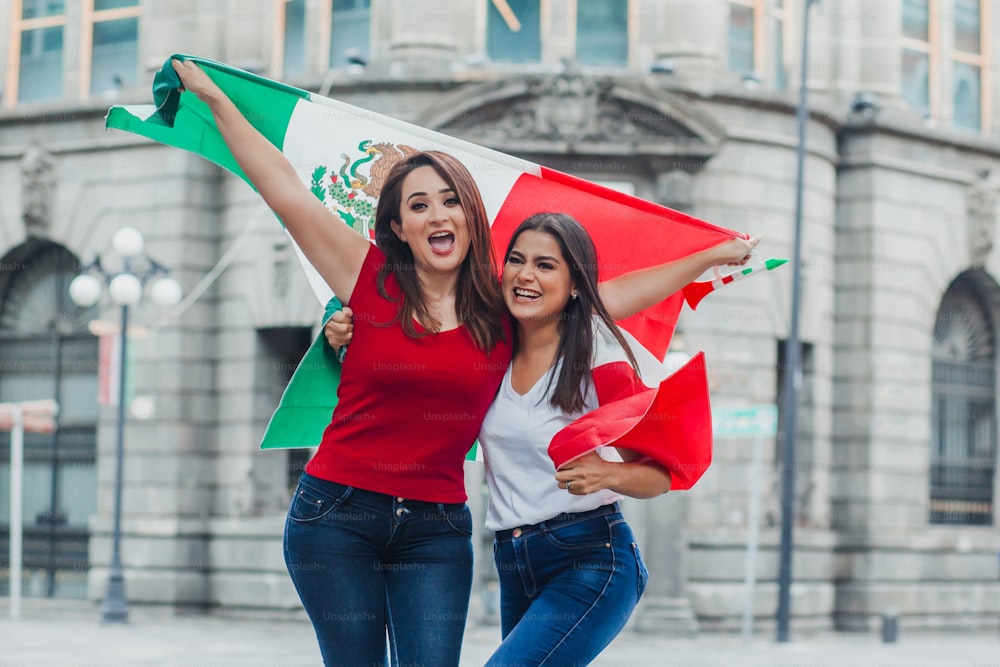 Mexikanische Freundinnen halten am Unabhängigkeitstag in Mexiko eine Flagge von Mexiko