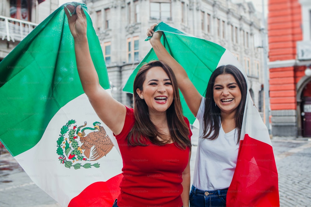 Amigas mexicanas en el Día de la Independencia en México sosteniendo una bandera de México