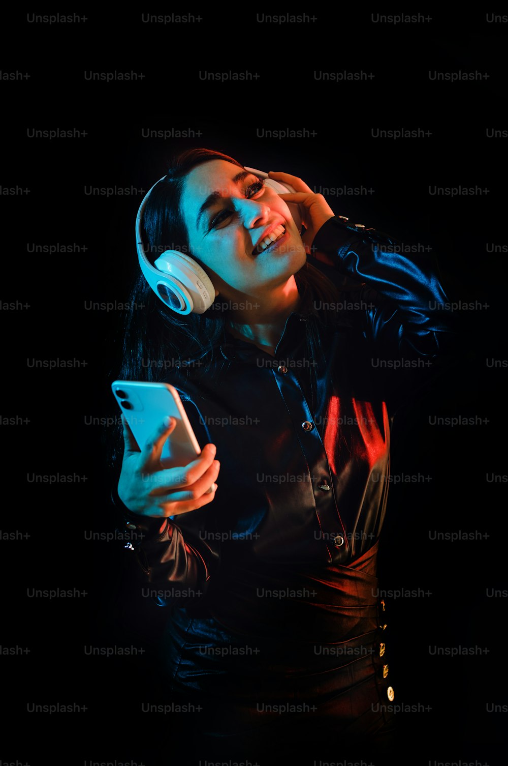lateinamerikanische junge Frau mit Kopfhörern, die Musik über Farbe Neon und schwarzen Hintergrund in Mexiko Lateinamerika hört