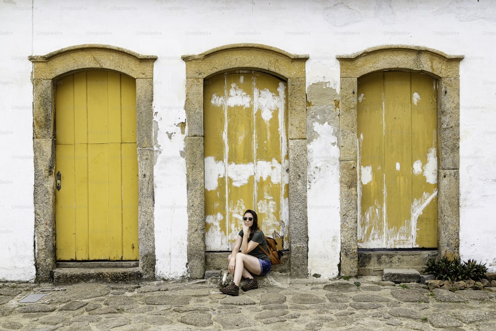 Hermosa modelo sentada en una puerta amarilla en la histórica ciudad de Paraty, Río de Janeiro, Brasil.