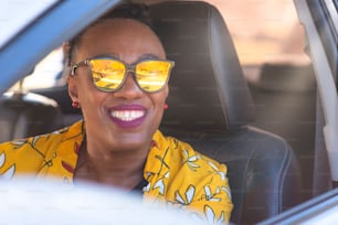 Portrait of lady in glasses smiling inside the car.