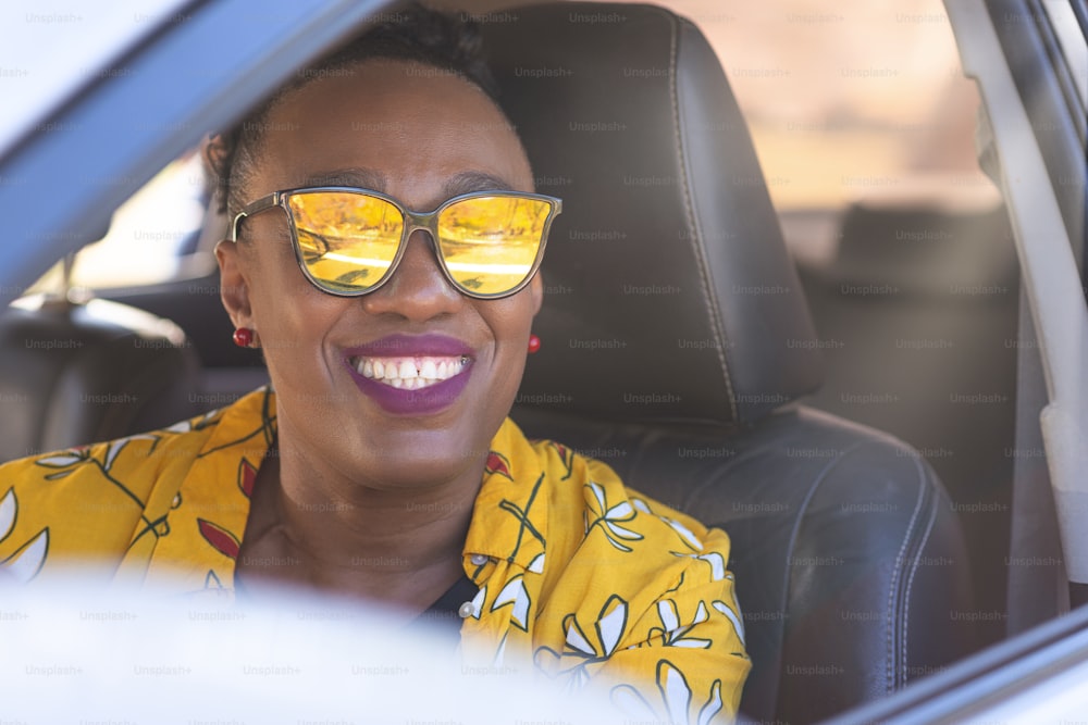 Porträt einer Dame mit Brille, die im Auto lächelt.