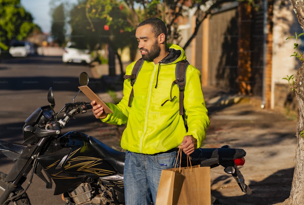Portrait of delivery man with his motorcycle with delivery. Parcel delivery concept.