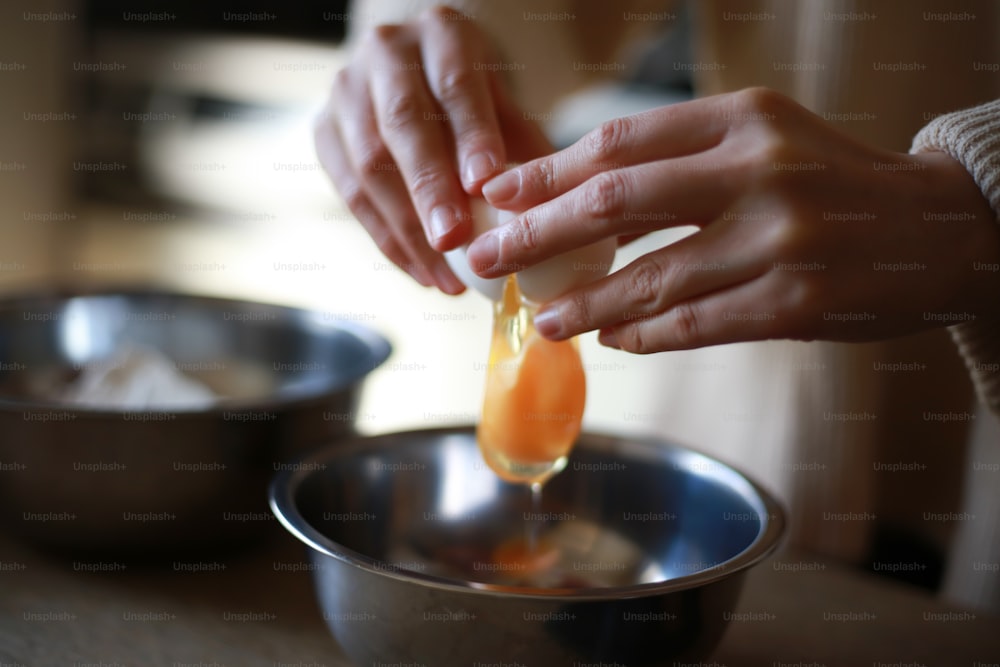 The hand of a woman breaking an egg