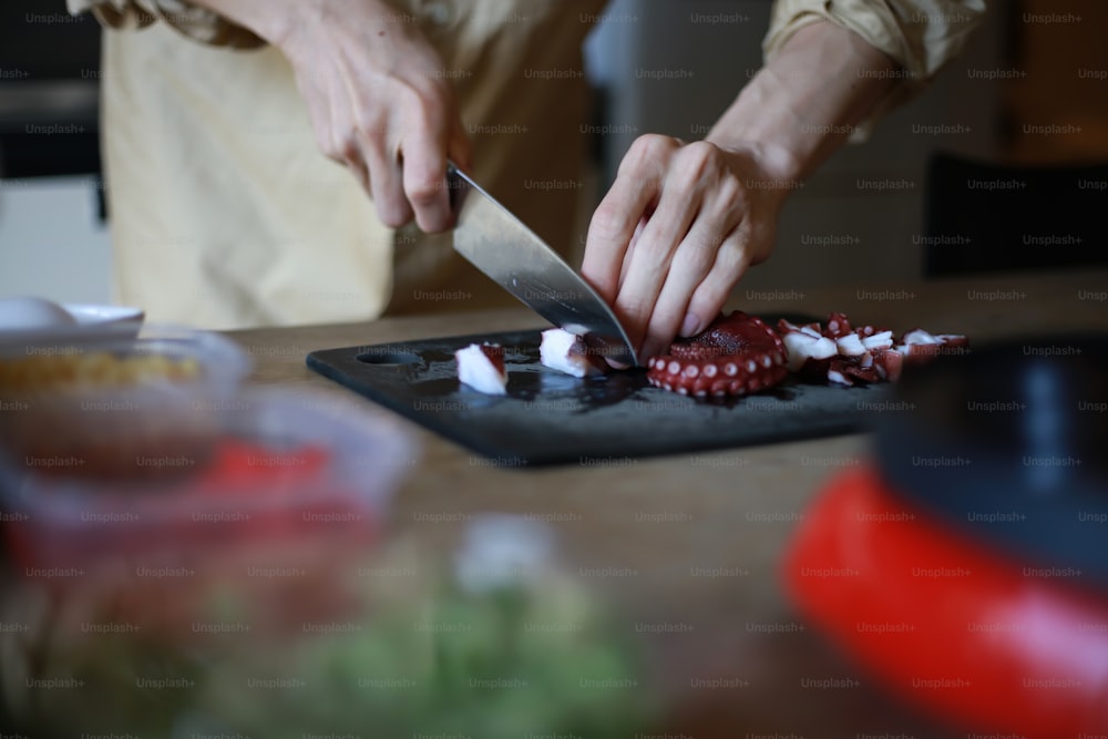 Hands of a man who cuts an octopus