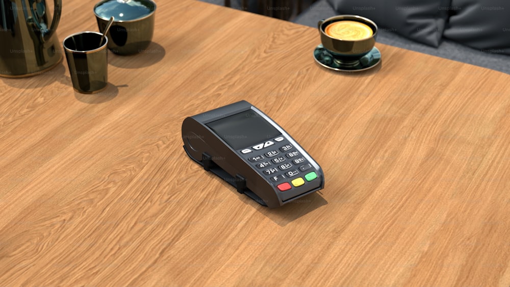 a wooden table topped with a calculator next to a cup of coffee