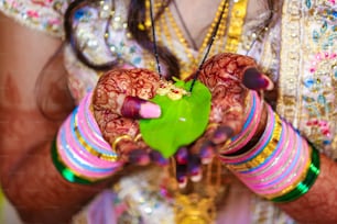 Noivo indiano e noiva segurando mangalsutra ou colar de ouro com folha verde na mão