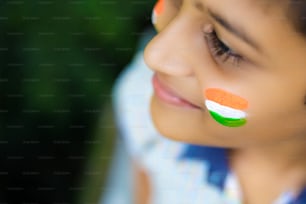 Kleines indisches Kind mit indischer Flagge im Gesicht
