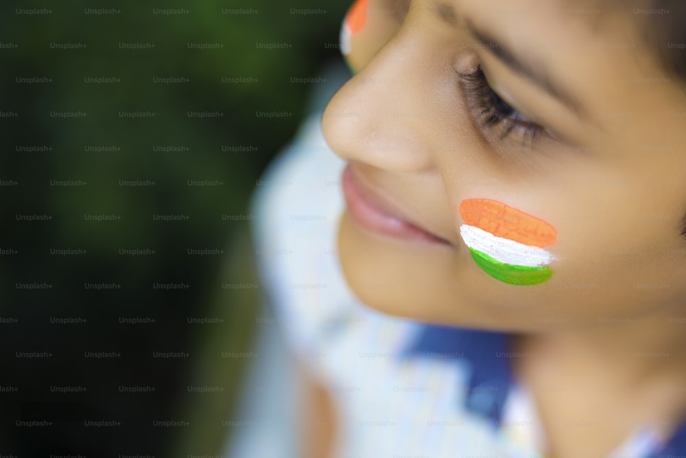 Giovane bambino indiano con la bandiera indiana sul viso