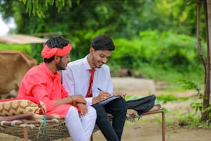 Young indian farmer sign on document with banker at home